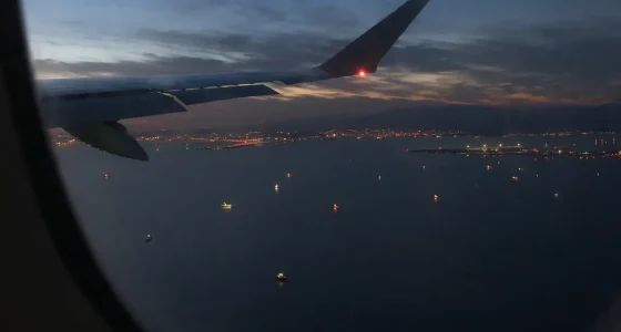 Vy från flygplansfönster över Hormuzsundet med fartygsljus i vattnet och kustljus i horisonten